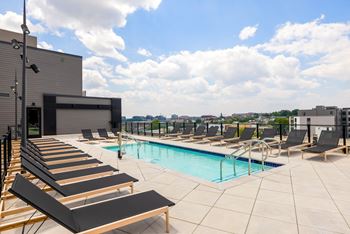 A swimming pool on the roof of a building with lounge chairs